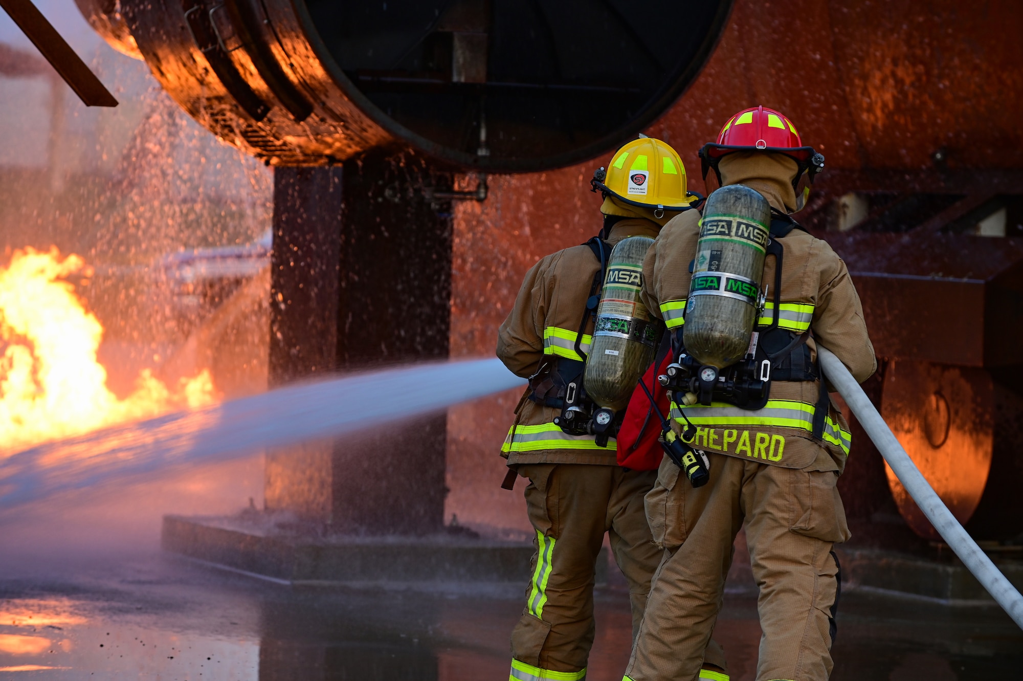Two U.S. Air Force firefighters with the 31st Civil Engineer Squadron put out a training fire at Aviano Air Base, Italy, Oct. 12, 2022. 31st CES Fire Department firefighters extinguished the fire during a demonstration for Aviano AB families and allies. (U.S. Air Force photo by Senior Airman Thomas S. Keisler IV)