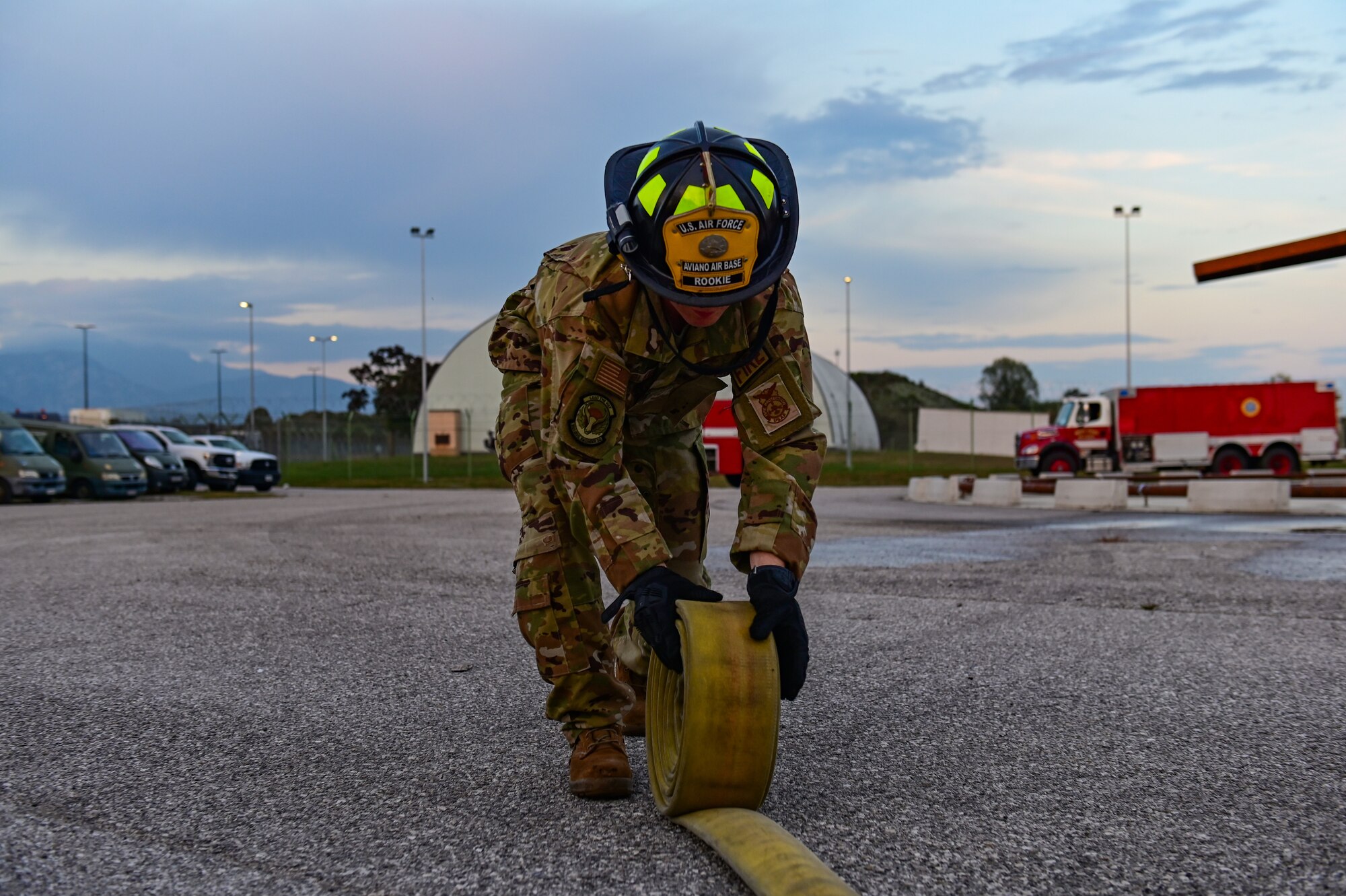A U.S. Air Force firefighter with the 31st Civil Engineer Squadron rolls up a hose after a live fire exercise at Aviano Air Base, Italy, Oct. 12, 2022. The 31st CES fire department provides fire, rescue, and emergency services to Aviano AB. (U.S. Air Force photo by Senior Airman Thomas S. Keisler IV)