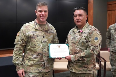 Lt. Col. Joseph Harris, the Recruiting and Retention Battalion commander, presents a Meritorious Service Medal to Sgt. 1st Class Justin Wolfe, of Sycamore, Illinois, during his retirement ceremony at Camp Lincoln in Springfield, Illinois, October 13.