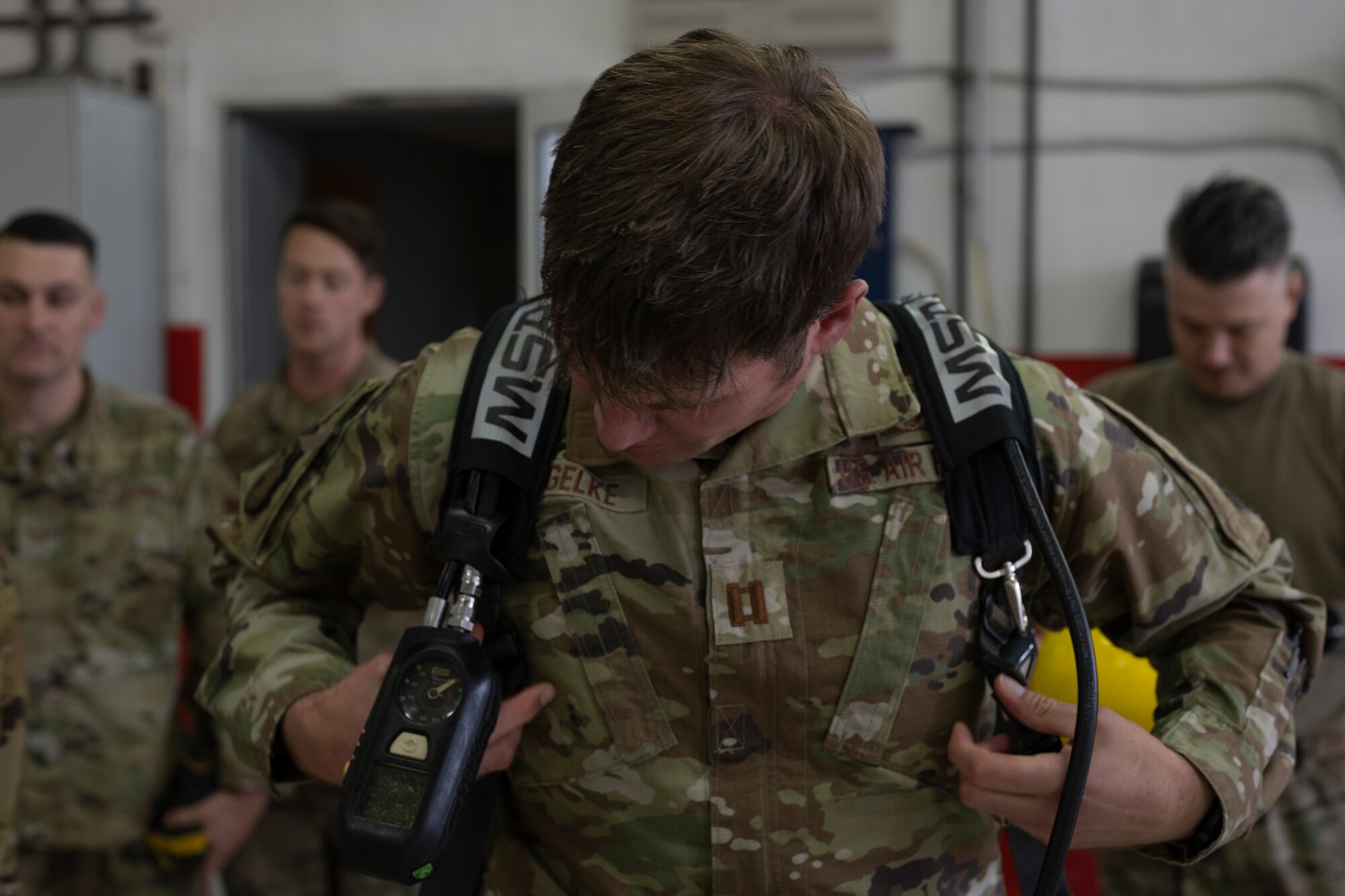 An airman puts on a breathing apparatus tank.