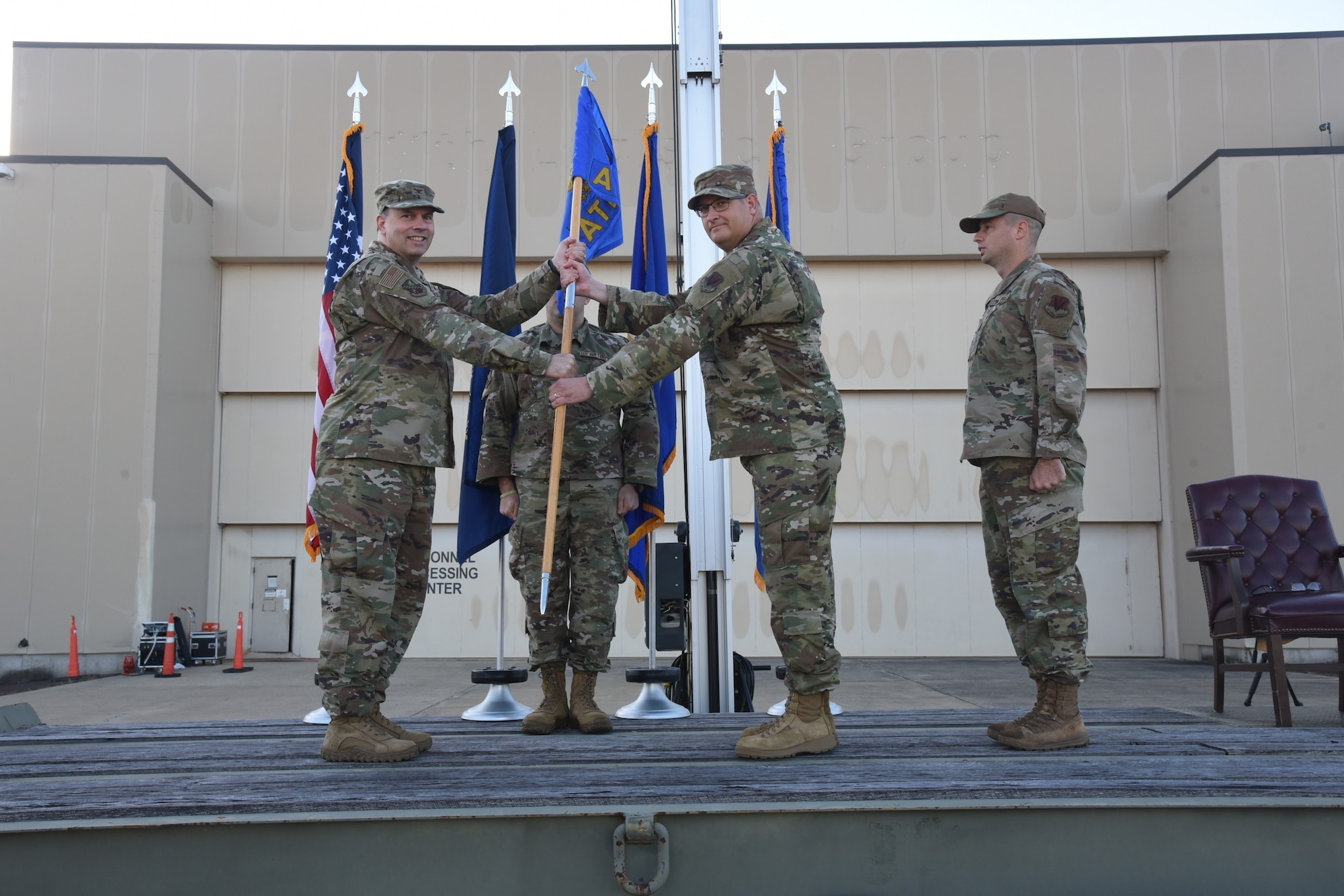 A man in an Air Force Uniform accepts a flag from another man in uniform.