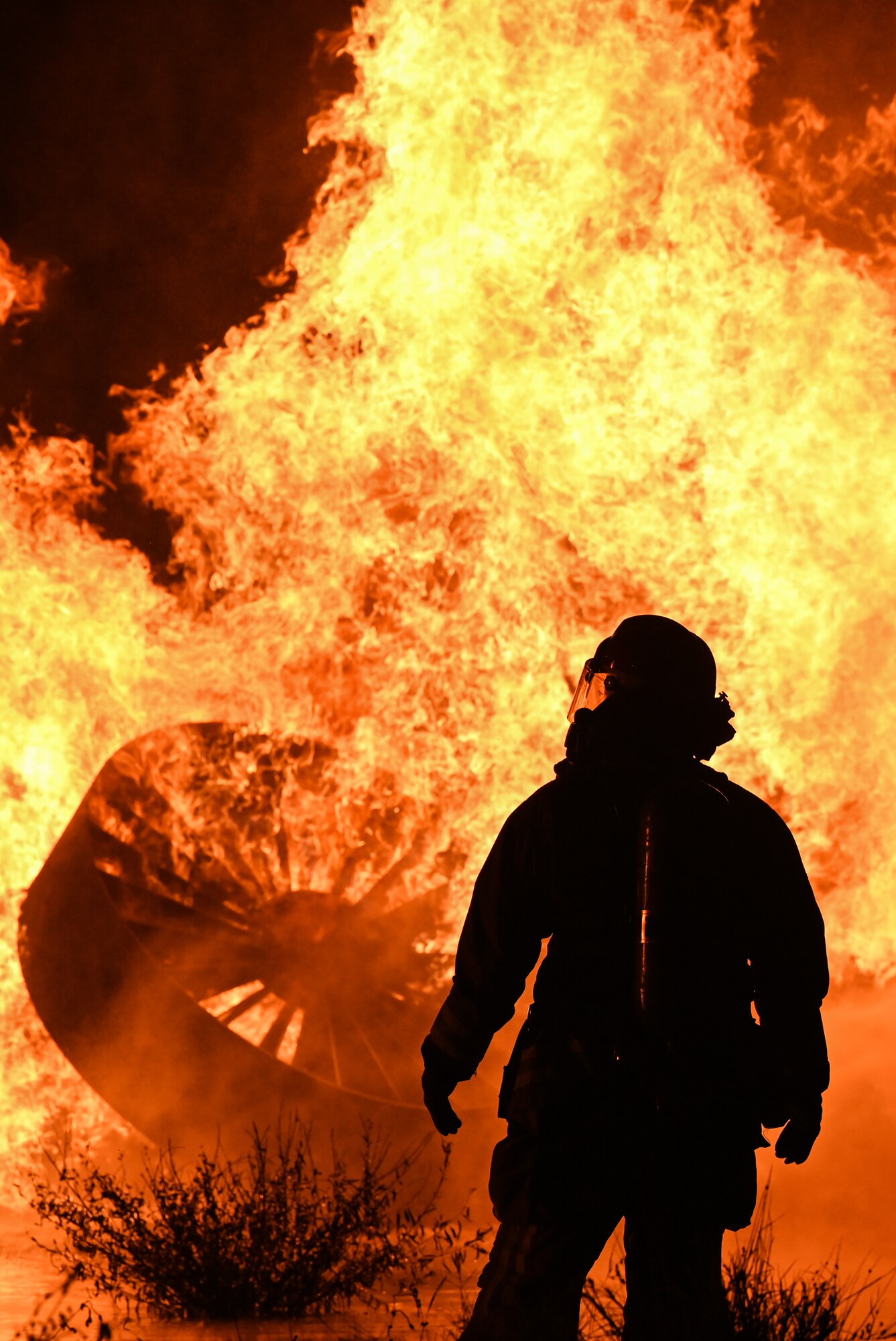 A firefighter from the 97th Civil Engineer Squadron observes as other firefighters put out a fire during a live-burn training at Altus Air Force Base (AAFB), Oklahoma, Oct. 12, 2022. Live burns during Fire Prevention Week are showcased to the public to display the capabilities of AAFB fire personnel. (U.S. Air Force photo by Senior Airman Kayla Christenson)