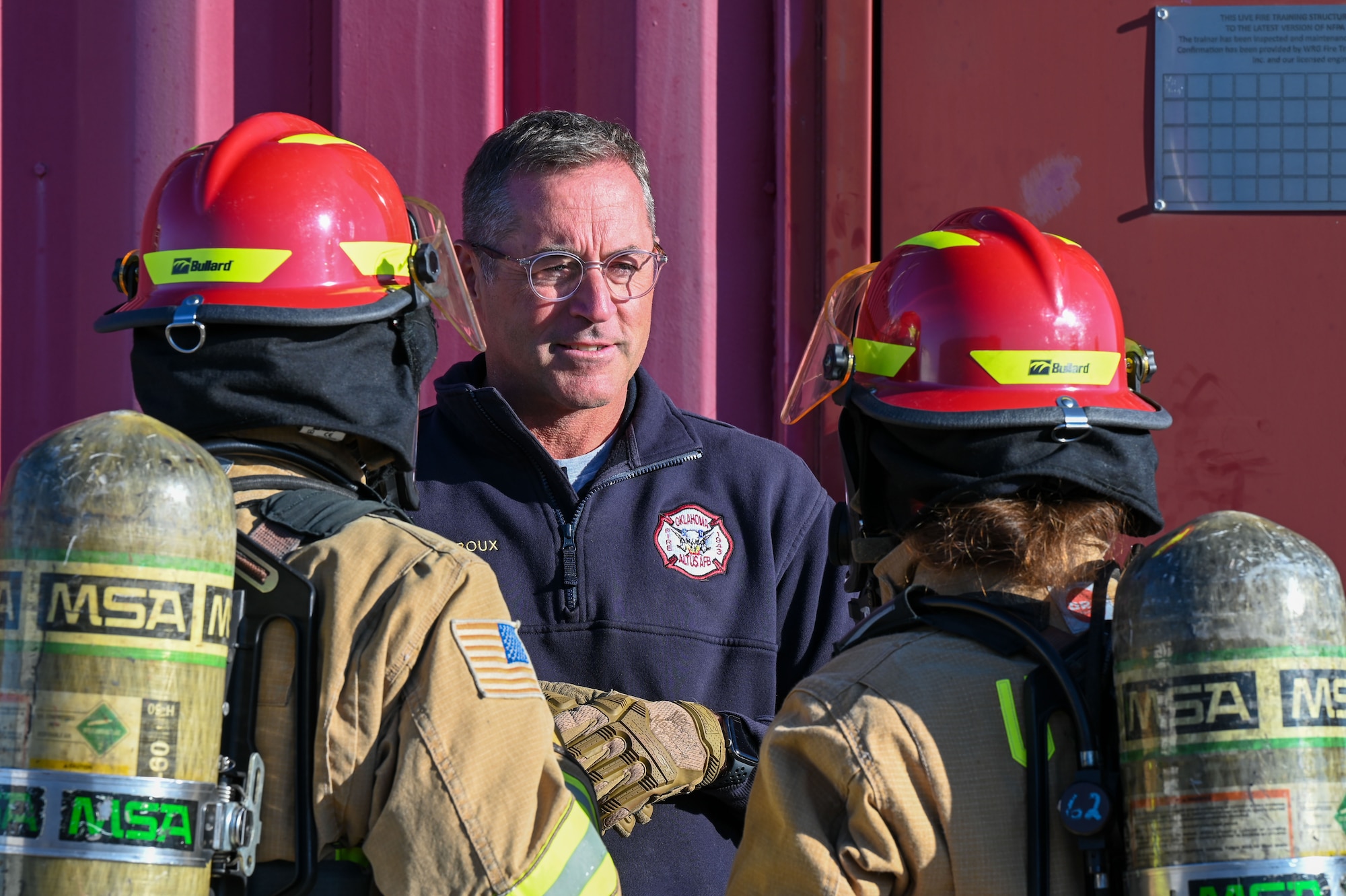 Phillip Fourroux, 97th Civil Engineer Squadron fire chief, talks with U.S. Air Force Col. Hollister (left), 97th Mission Support Group commander, and Chief Master Sgt. Sue Thompson (right), 97th Mission Support Group senior enlisted leader, before a Fire Prevention Week challenge at Altus Air Force Base, Oklahoma, Oct. 14, 2022. The challenge gave an opportunity to group commanders and senior enlisted leaders to complete an obstacle course that involved the participants crawling through a small space with full firefighter gear on. (U.S. Air Force photo by Senior Airman Kayla Christenson)