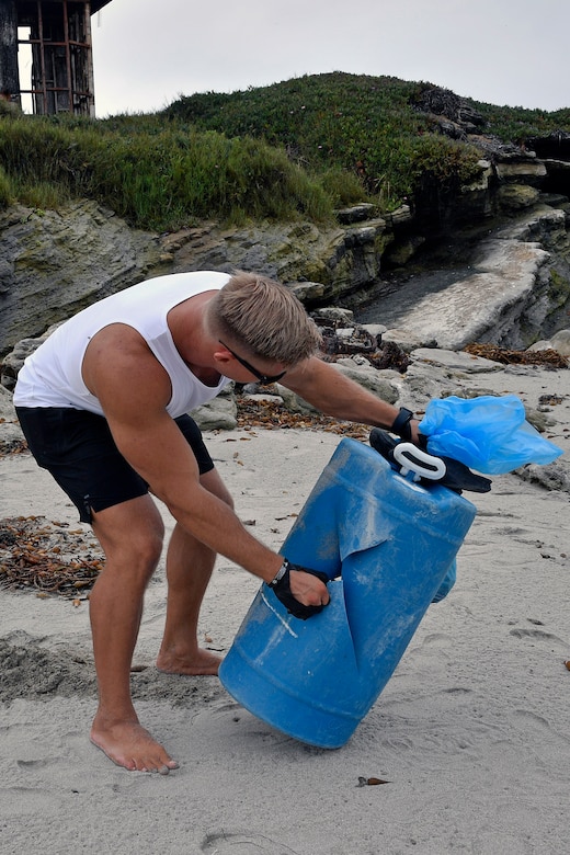 A man picks up trash on a beach.