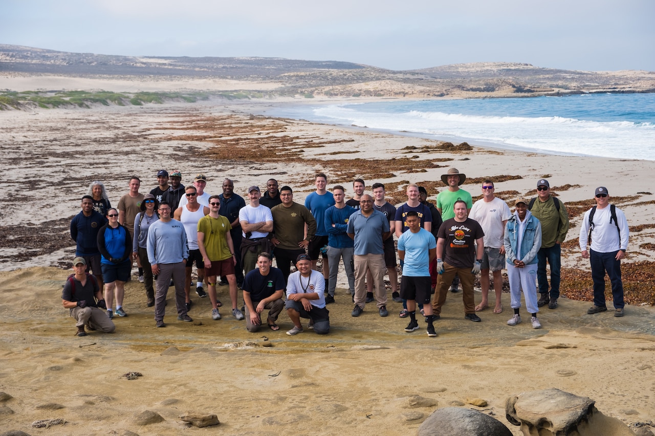 A group of people pose for a photo on a beach.