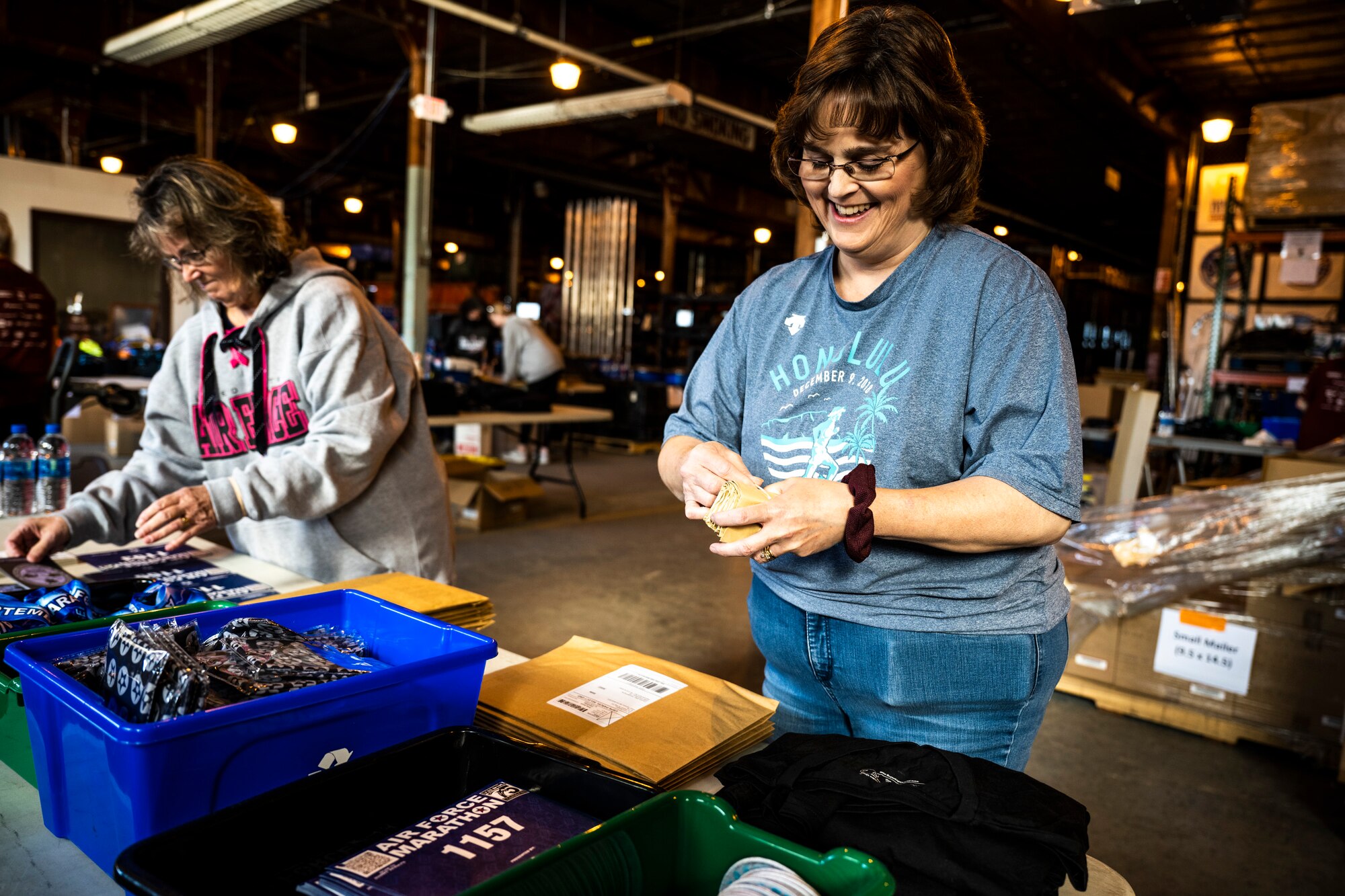 Air Force Marathon volunteers pack participation merchandise in warehouse.