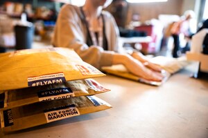 An Air Force Marathon volunteer packs participation merchandise at a table. Packing sticker reads #FlyAFM
