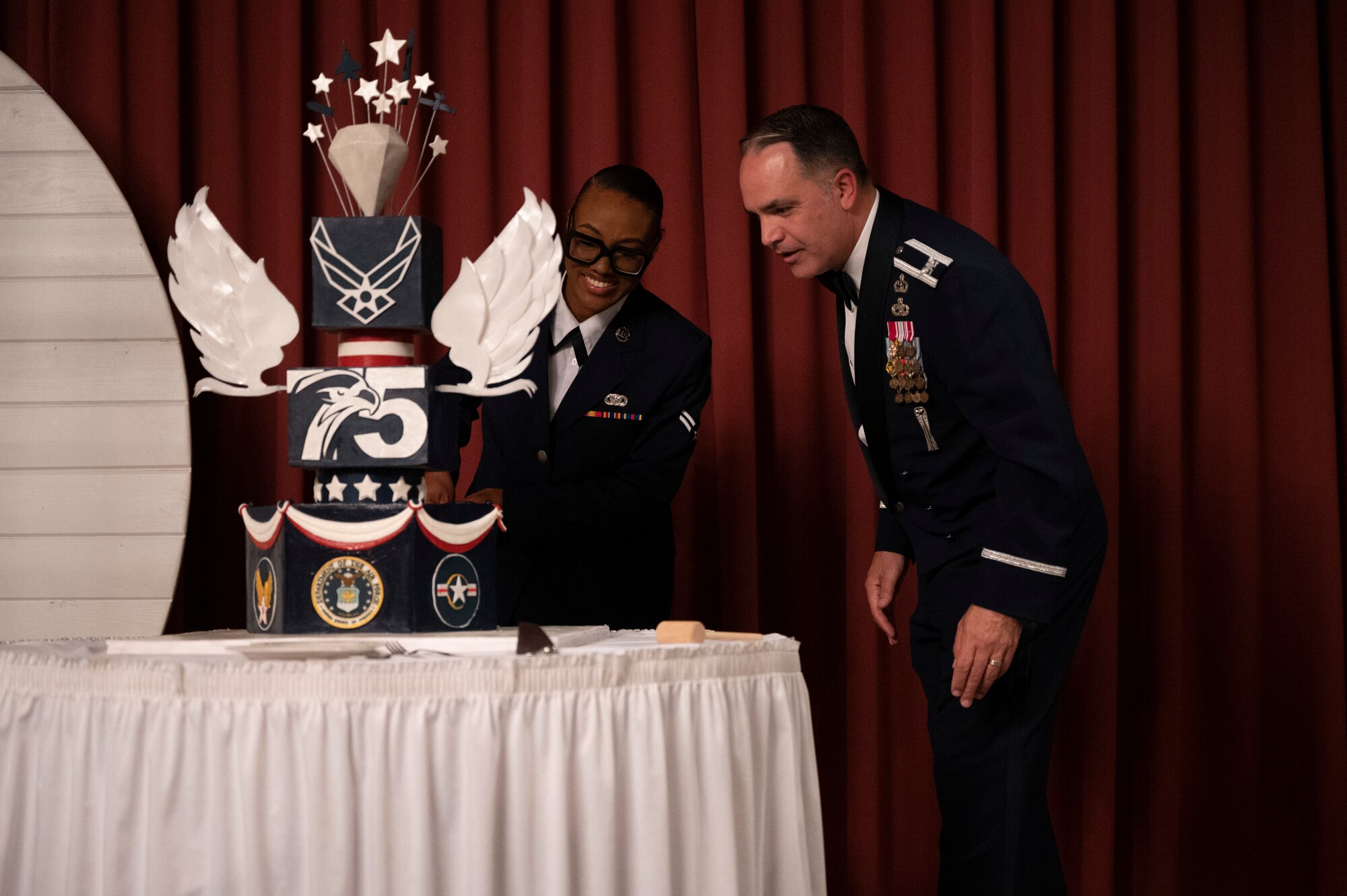 A man and woman cut a cake on stage.