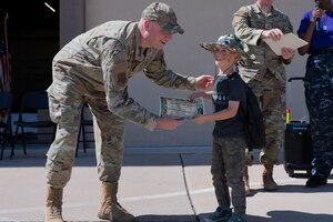 U.S. Air Force Col. Matthew Reilman, 17th Training Wing commander, presents a certificate to Samuel Corbett, military child, at the conclusion of the 2022 Operation Kids event at the Vance Deployment Center, Goodfellow Air Force Base, Texas, Oct. 15, 2022. The event culminated with a welcome home celebration for the children returning from their mock deployment. (U.S. Air Force photo by Senior Airman Michael Bowman)