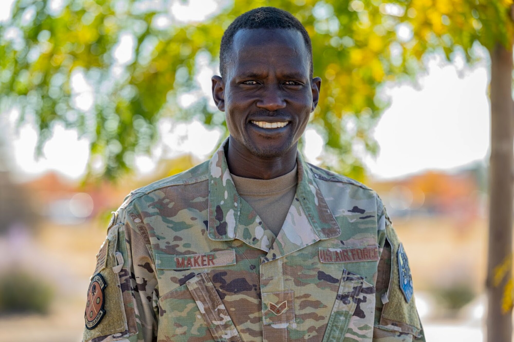 Airman poses for a photo in front of trees