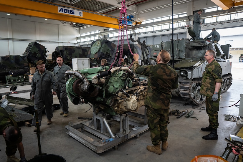 Soldiers work on a vehicle engine.