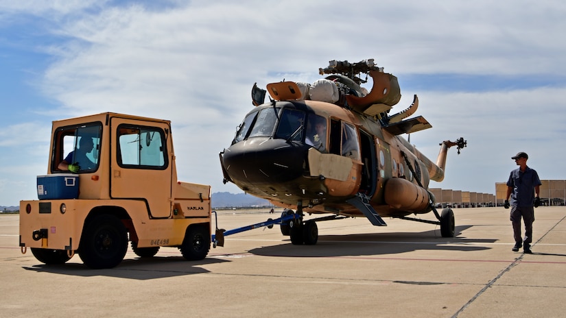 A tractor tows a helicopter.