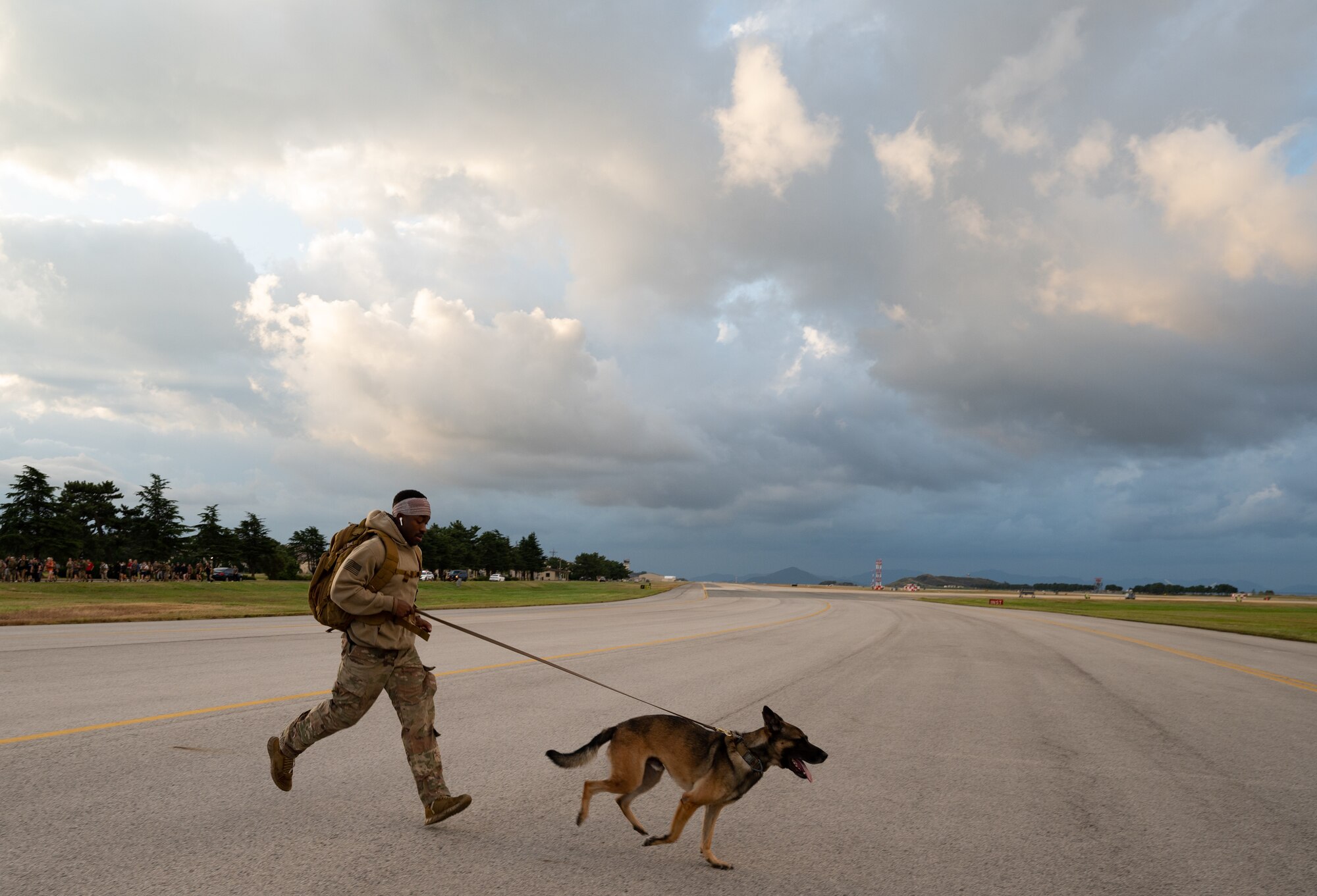 Senior Airman Justin Collins, 8th Security Forces Squadron military working dog handler, and MWD Taro, run during a Prisoner of War and Missing in Action ruck event at Kunsan Air Base, Republic of Korea, Oct. 7, 2022. The SFS MWD handlers brought many MWDs out to participate in the Wing event to honor POW/MIA servicemembers. (U.S. Air Force photo by Staff Sgt. Sadie Colbert)