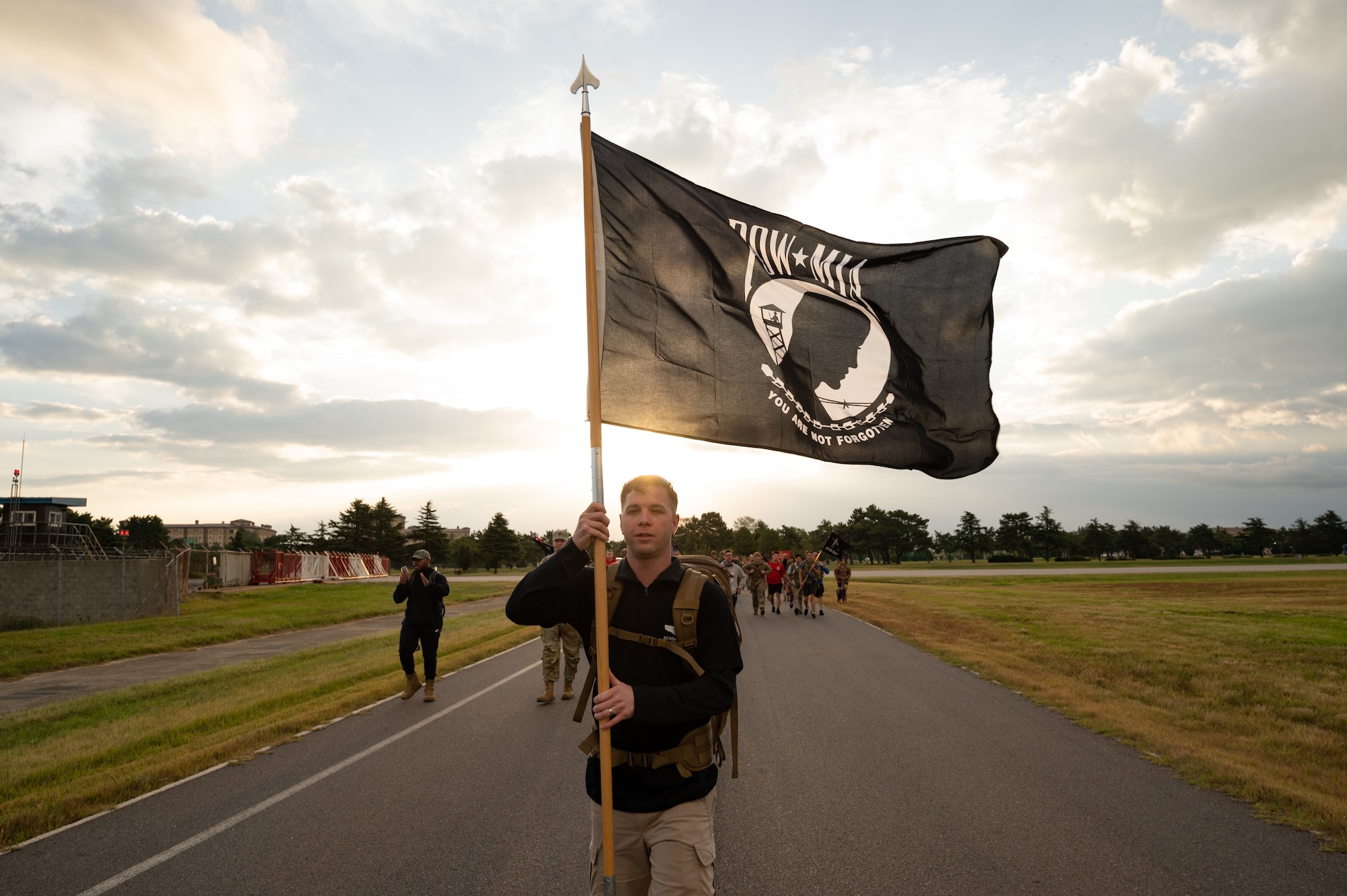 Tech. Sgt. Mark Henry, 8th Security Forces Squadron NCO in charge of investigations, carries a Prisoner of War and Missing in Action flag during a ruck event at Kunsan Air Base, Republic of Korea, Oct. 7, 2022. During the event, several service members from various squadrons took turns holding the POW/MIA flag. (U.S. Air Force photo by Staff Sgt. Sadie Colbert)