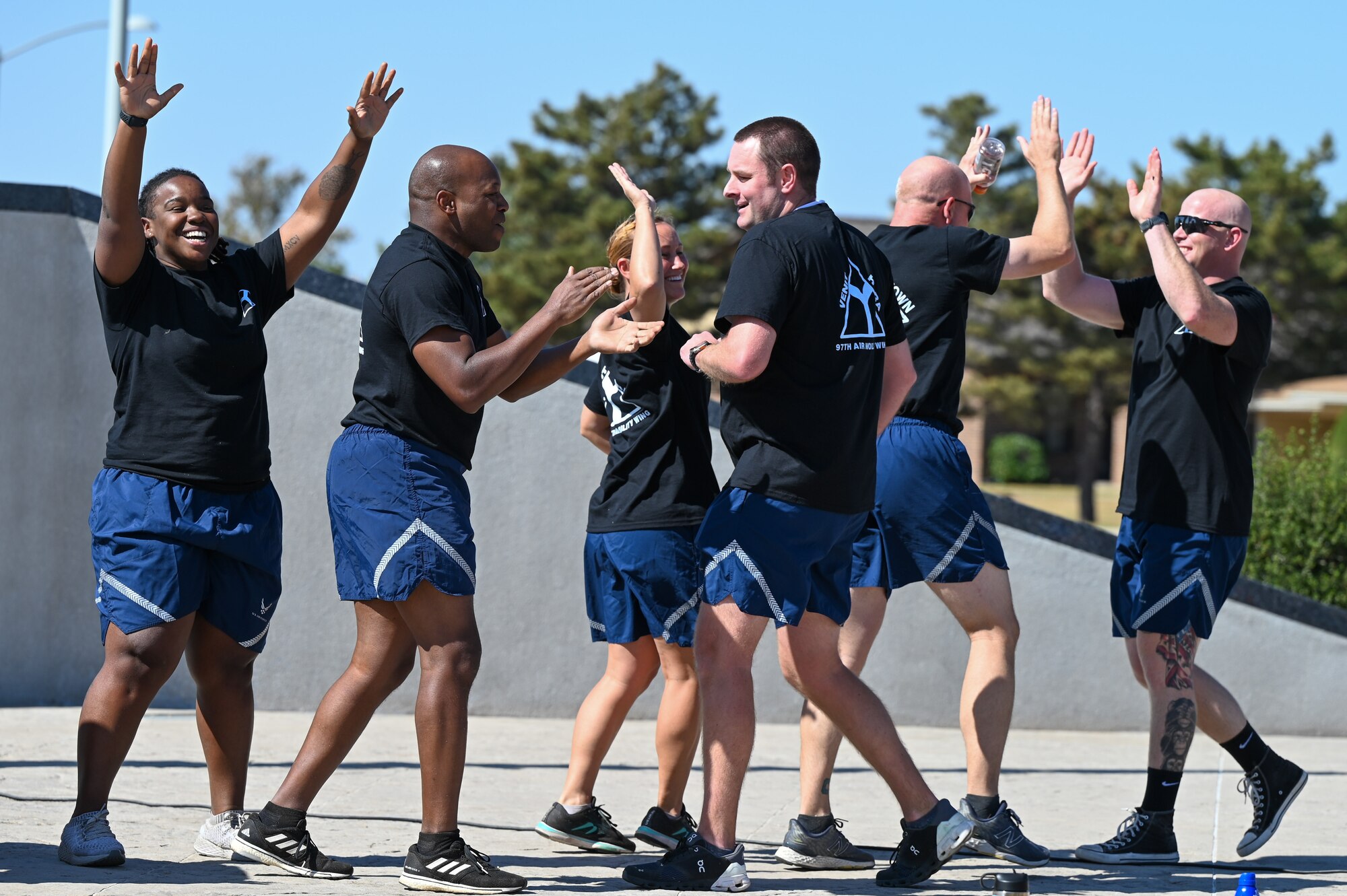 Airmen from the 97th Air Mobility Wing celebrate after winning a challenge during Fire Prevention Week at Altus Air Force Base, Oklahoma, Oct. 14, 2022. The challenge consisted of several tests that resembled what firefighters do to prevent and put out fires. (U.S. Air Force photo by Senior Airman Kayla Christenson)