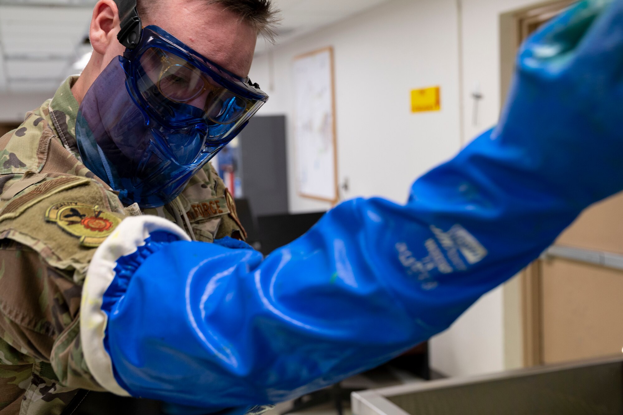 A man dons a pair of blue gloves to protect himself from hazardous materials.