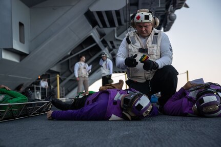 A Sailor provides emergency medical care to a simulated victim during a mass casualty drill on the ship's aircraft elevator, Oct. 14, 2022.