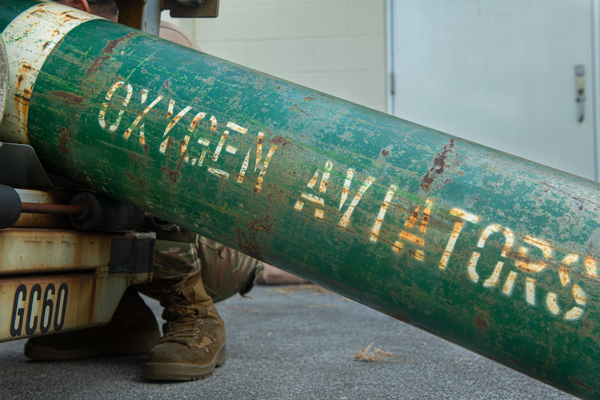 An oxygen bottle lays beside a gaseous oxygen cart.