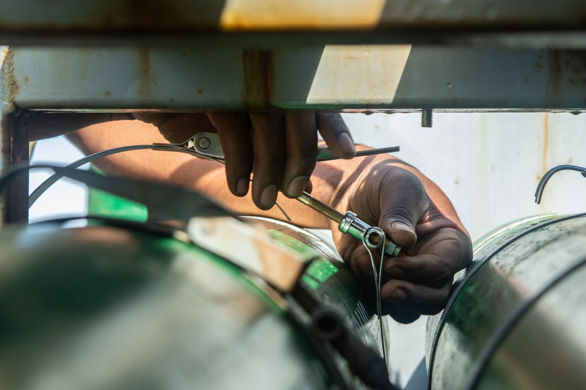 An Airman's hands grasp an oxygen bottle clamp.