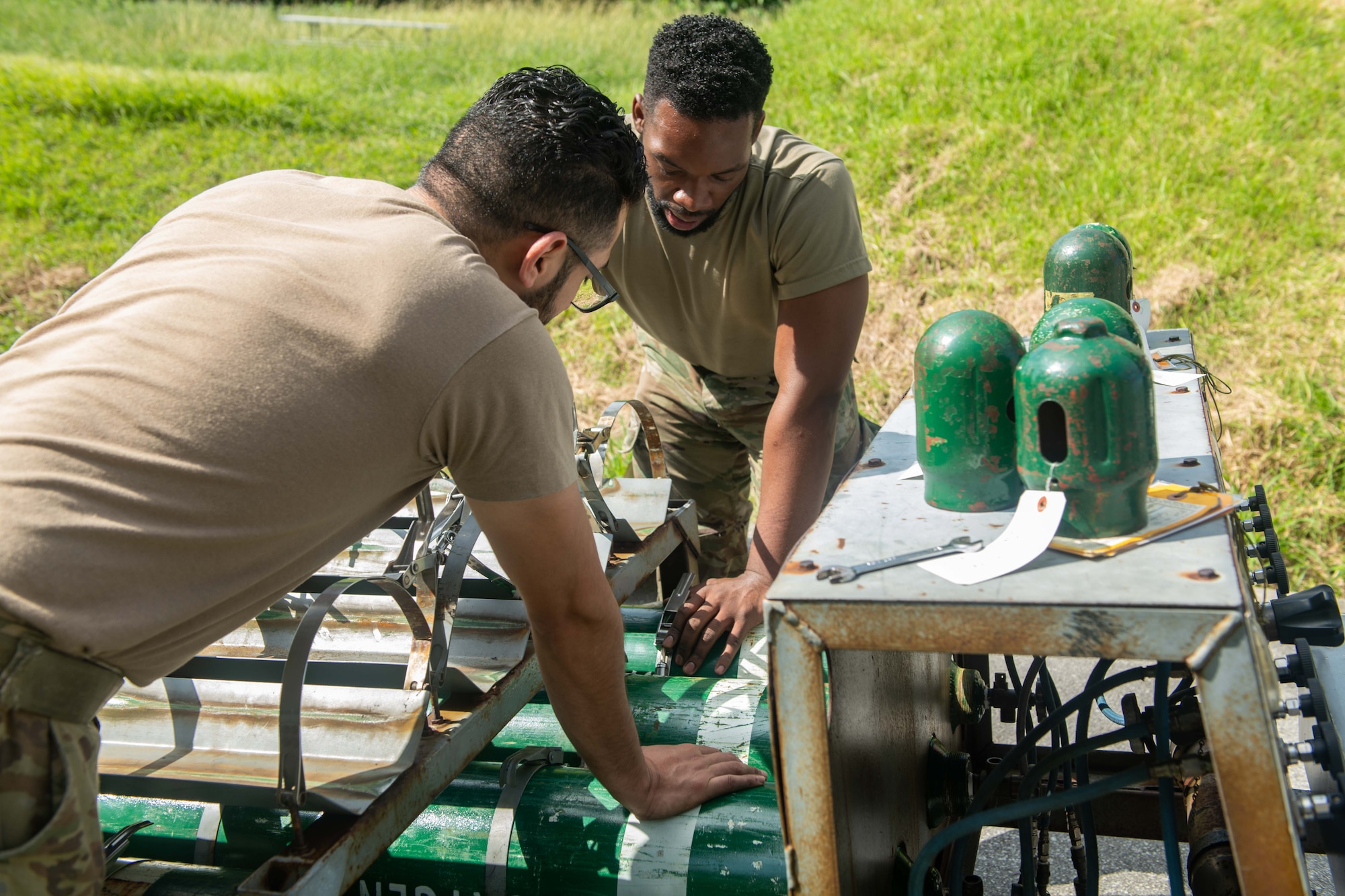 Two Airmen work on a gaseous oxygen cart.