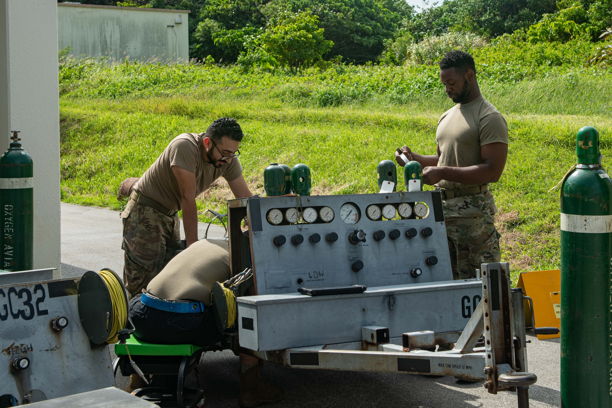Three Airmen work on a gaseous oxygen cart.