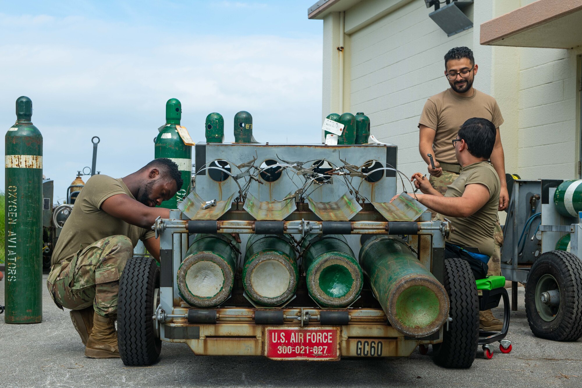 Three Airmen work on a gaseous oxygen cart.