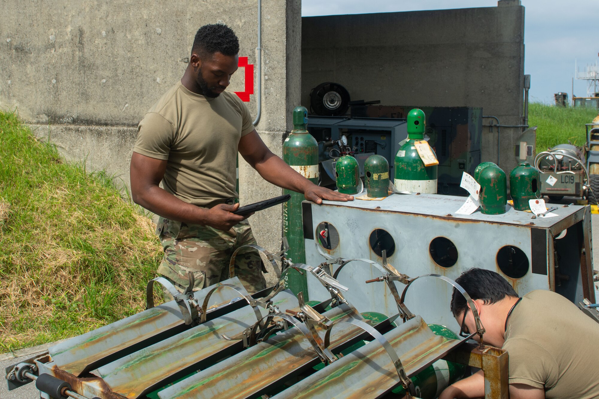 Airman reads technical order in front of a gaseous oxygen cart.