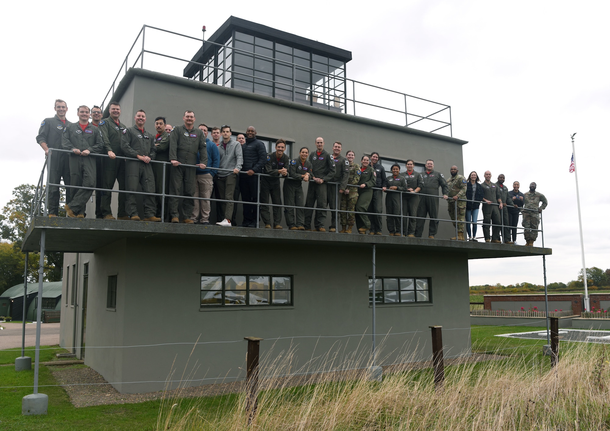 U.S. Air Force Airmen from the 351st Air Refueling Squadron gather on the Thorpe Abbotts air traffic control tower after a patching ceremony at the 100th Bomb Group Memorial Museum at Thorpe Abbotts, England, Oct. 14, 2022. The patching ceremony tradition dates back to World War II and the “Buzzard” patch, presented to pilots and boom operators who have completed mission certification training, is the patch of the 351st Bomb Squadron which flew out of Thorpe Abbotts during World War II. (U.S. Air Force photo by Karen Abeyasekere)