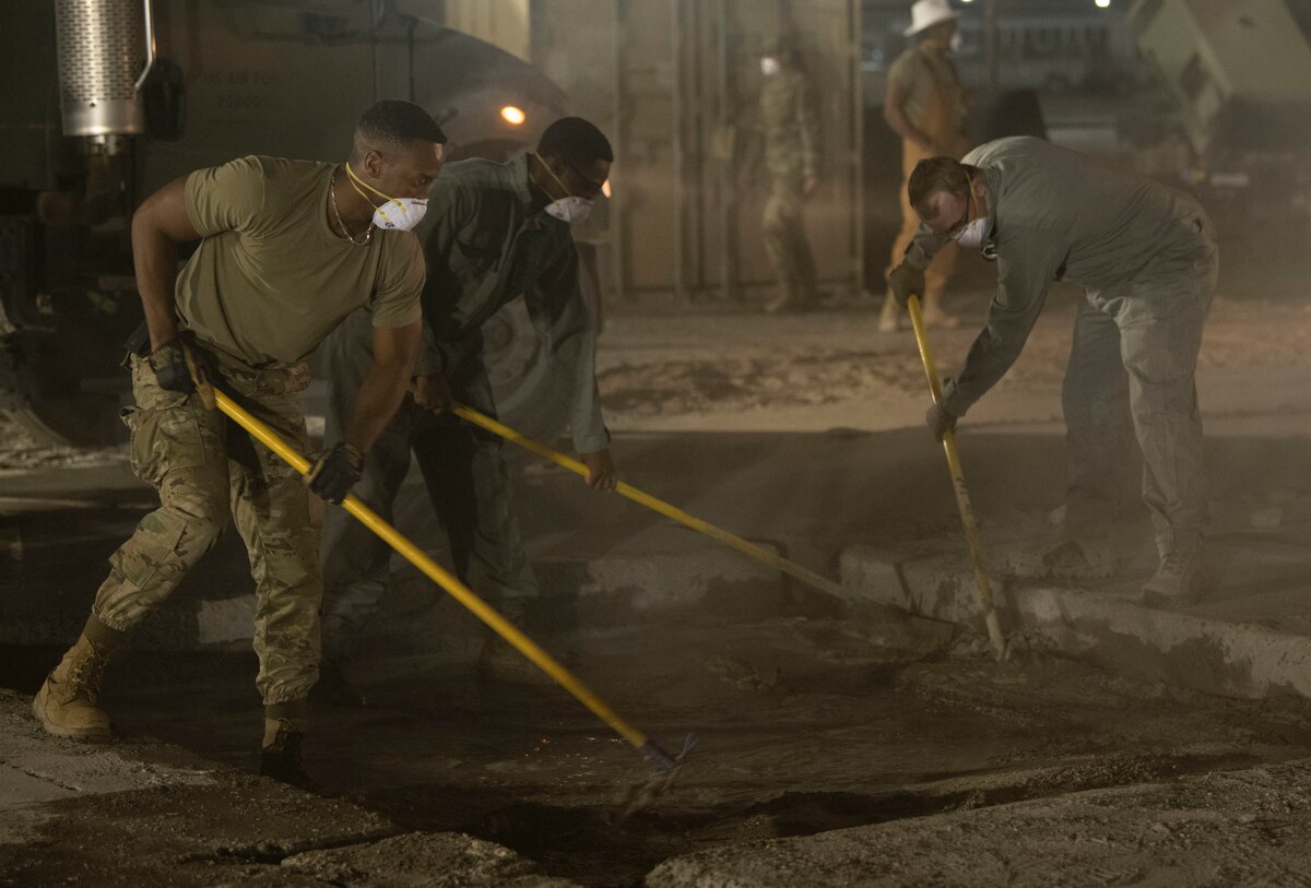 U.S. Air Force Senior Airman Mark Morgan, 386th Expeditionary Civil Engineer Squadron structures journeyman, sweeps water over the dried cement during a Rapid Airfield Damage Recovery exercise at Ali Al Salem Air Base, Kuwait, October 7, 2022. 386th ECES Airmen demonstrated multi-capable Airmanship during the exercise by handling jobs outside of their day-to-day expertise. (U.S. Air Force photo by Staff Sgt. Ashley N. Mikaio)
