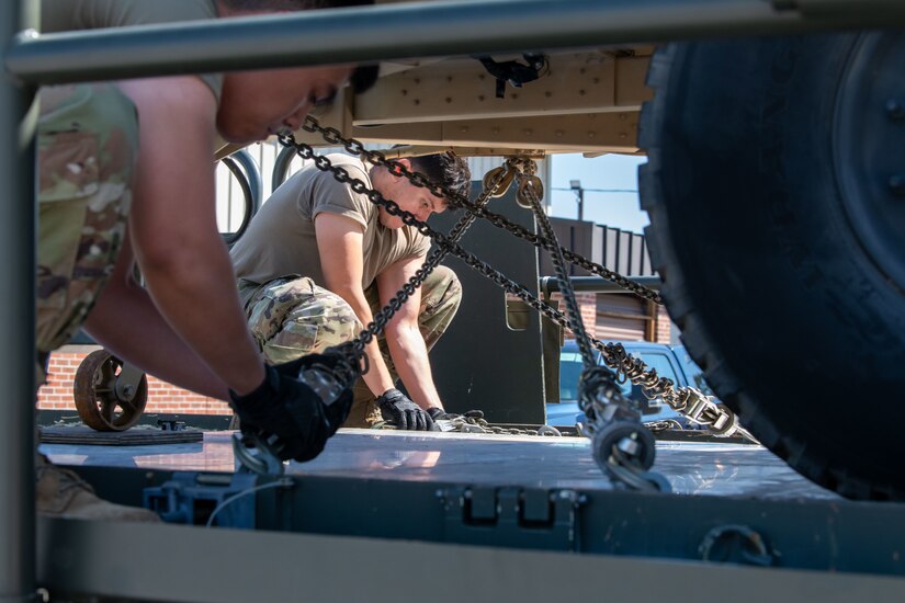 Airmen tie down a Humvee