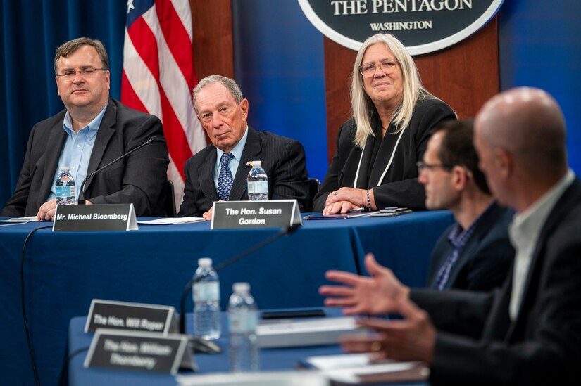 Three people sit at a table on the left. Two others sit at another table on the right.