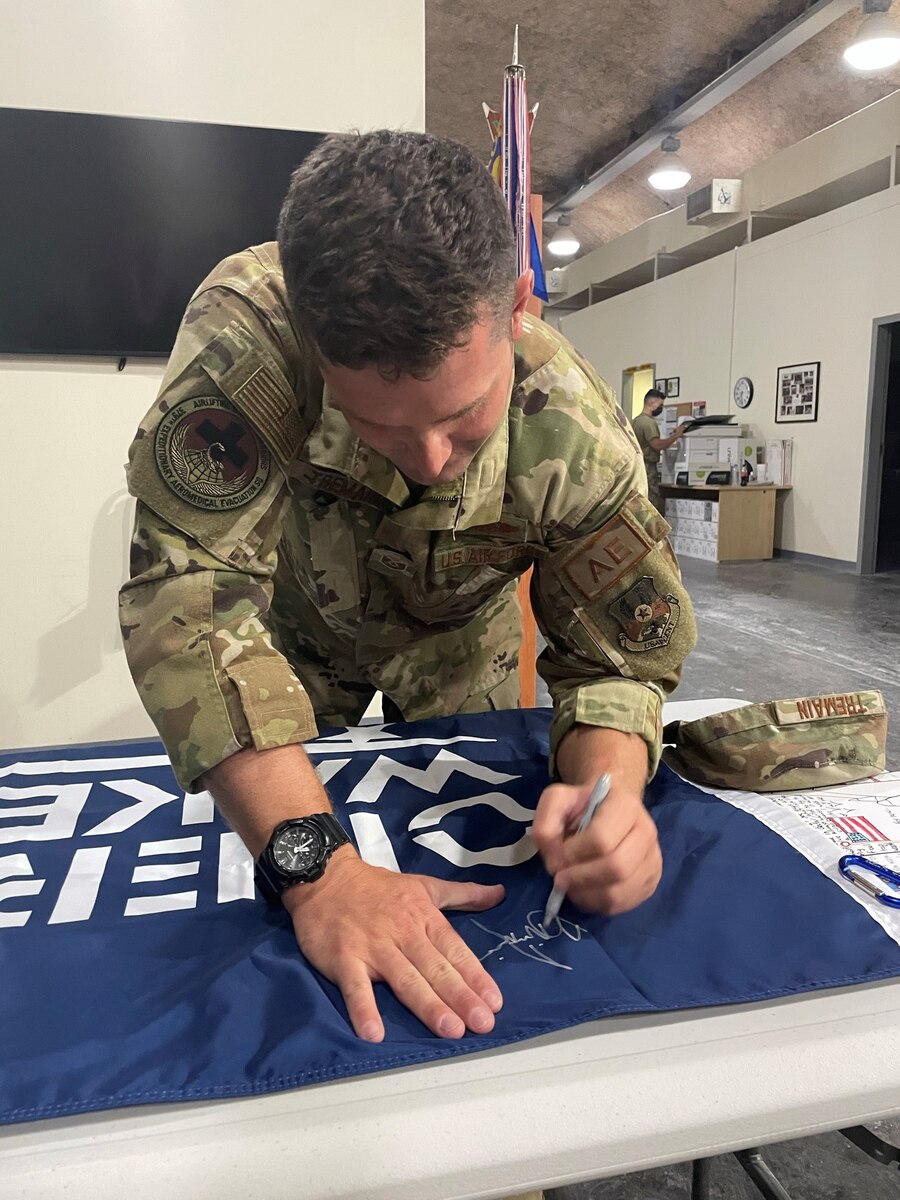 Master Sgt. Brian Tremain signs the Operation Wake Surf banner before it was flown on a mission in Afghanistan to fly home wounded warriors. (Courtesy photo)