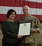 Sgt. 1st Class Charles Chinski, of Bourbonnais, Illinois, 244th Digital Liaison Detachment, based in Chicago, presents his wife, Elizabeth, a certificate of appreciation during a retirement ceremony Oct. 16 at the Northwest Armory in Chicago.