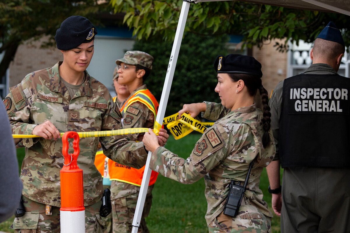 Senior Airman Gianni Perreira, left, 436th Security Forces Squadron response force leader, and Staff Sgt. Sidney Shaffer, right, 436th SFS lead evaluator, cordon off an area with police barricade tape prior to the start of an active shooter exercise held at Dover Air Force Base, Delaware, Oct. 14, 2022. The exercise involved numerous base and community first responders that worked together to neutralize the simulated active shooter during this joint training exercise. (U.S. Air Force photo by Roland Balik)