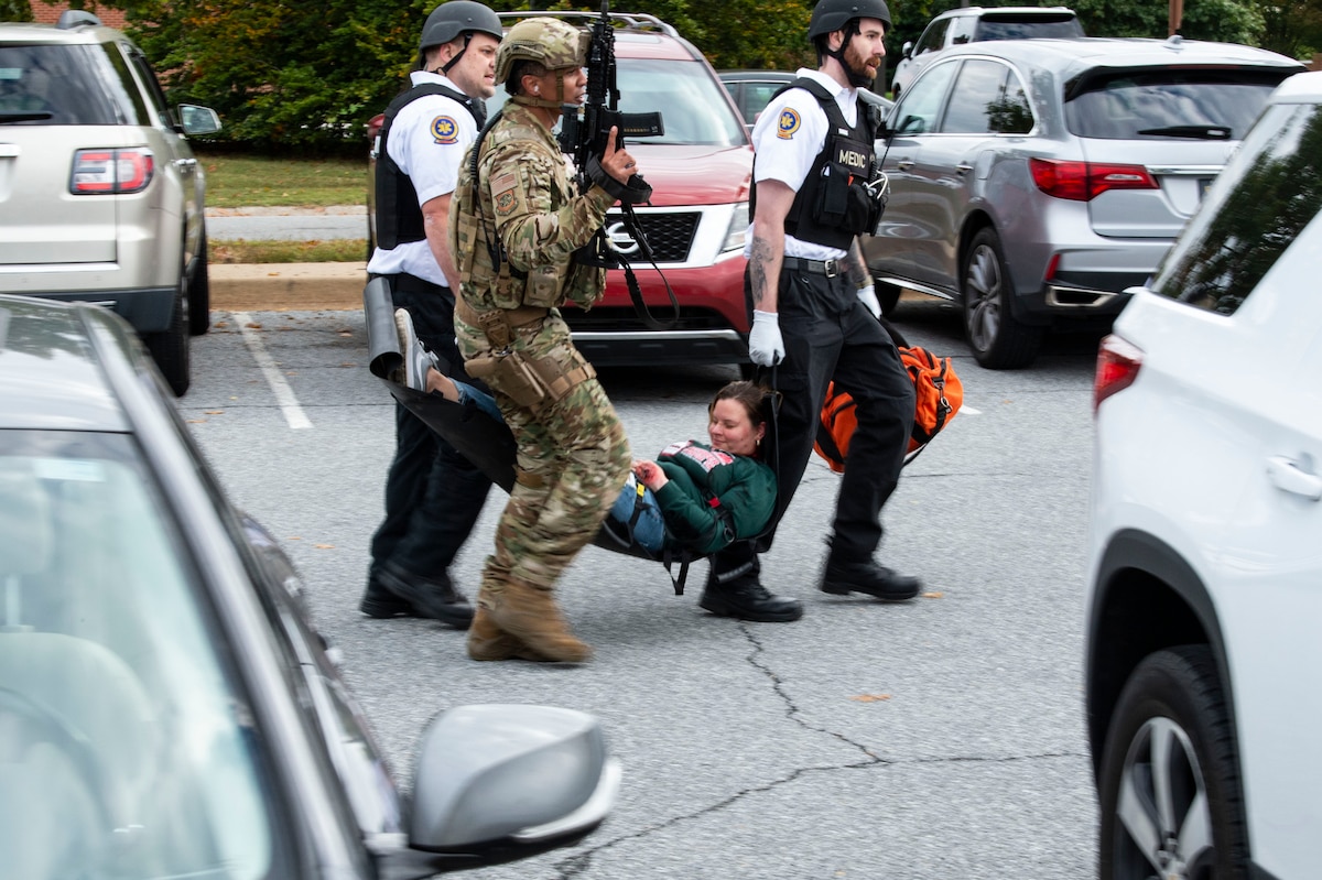 First responders carry away simulated shooting victim Staff Sgt. Kristina Grafton, 436th Operational Support Squadron executive assistant, to an awaiting Delaware State Police helicopter near Maj. George S. Welch Elementary and Dover Air Base Middle Schools during an active shooter exercise at Dover Air Force Base, Delaware, Oct. 14, 2022. Team Dover first responders worked with community agencies to neutralize the simulated active shooter, secure the scene, rescue hostages, care for the injured and recover casualties. (U.S. Air Force photo by Roland Balik)