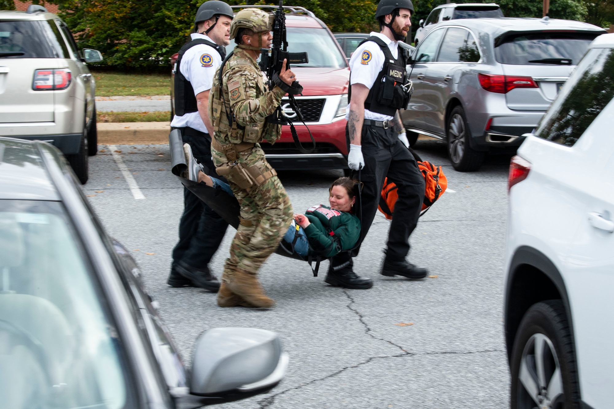 First responders carry away simulated shooting victim Staff Sgt. Kristina Grafton, 436th Operational Support Squadron executive assistant, to an awaiting Delaware State Police helicopter near Maj. George S. Welch Elementary and Dover Air Base Middle Schools during an active shooter exercise at Dover Air Force Base, Delaware, Oct. 14, 2022. Team Dover first responders worked with community agencies to neutralize the simulated active shooter, secure the scene, rescue hostages, care for the injured and recover casualties. (U.S. Air Force photo by Roland Balik)