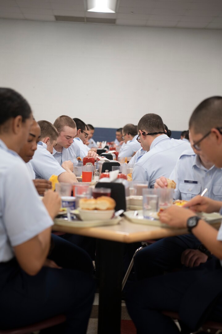 U.S. Air Force basic trainees from the 331st Training Squadron, Flight 677, sit in long rows and eat lunch during basic military training Sept. 20, 2022, at Joint Base San Antonio-Lackland, Texas.