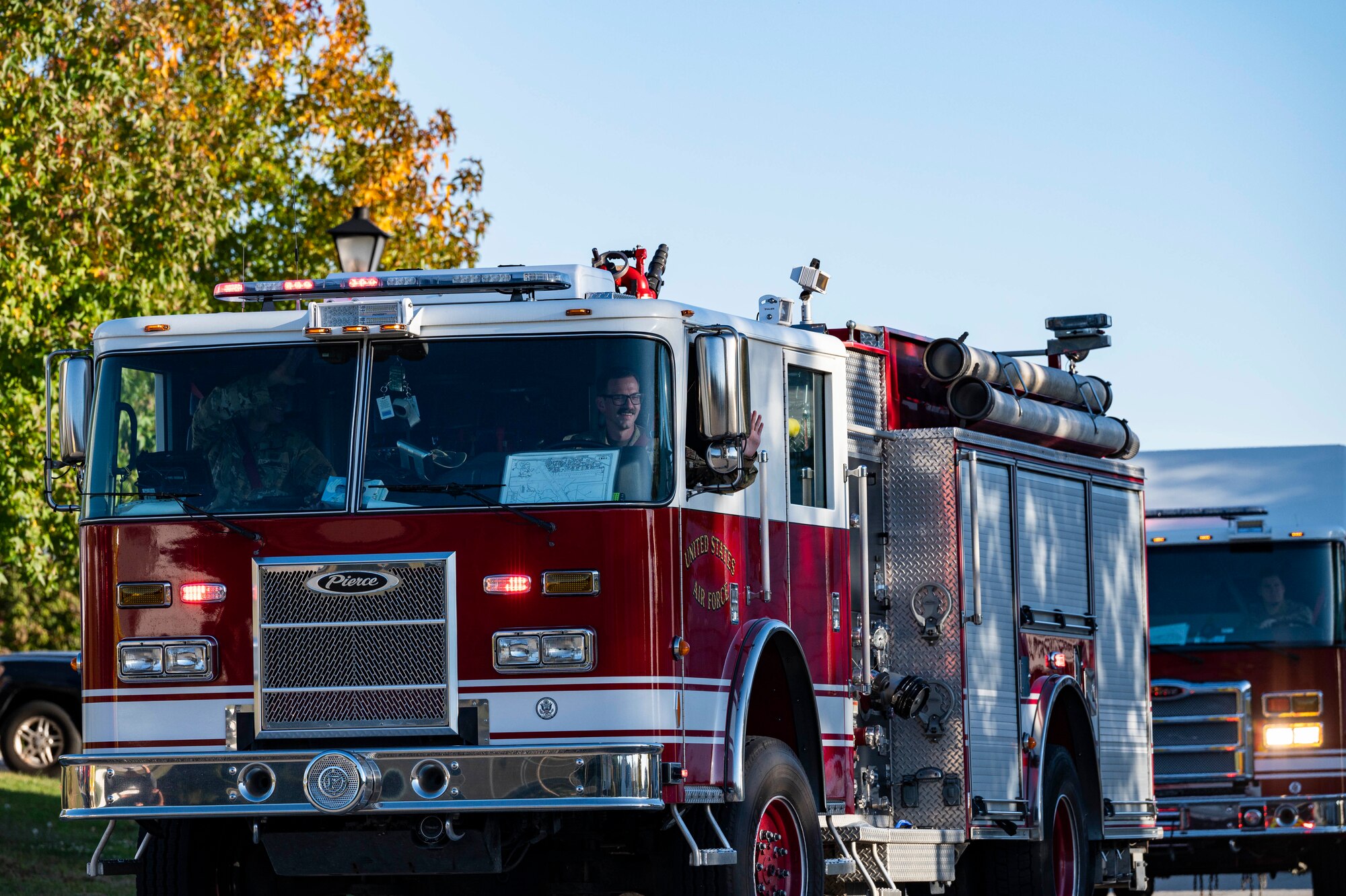 436th Civil Engineer Squadron Airmen wave to housing residents from an emergency service vehicle during the 2022 Fire Prevention Week parade at Dover Air Force Base, Delaware, Oct. 14, 2022. Dover AFB fire and emergency services drove through base housing to spread awareness on fire prevention week to base housing residents and their families. (U.S. Air Force photo by Staff Sgt. Marco A. Gomez)