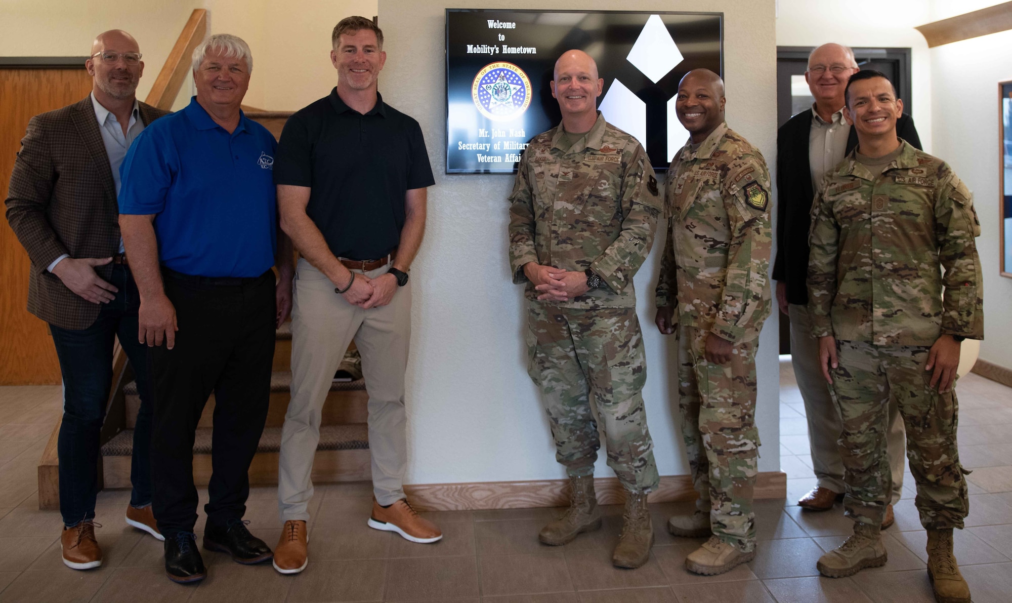 John Nash (center left), Secretary of Military and Veteran Affairs of Oklahoma, poses with the 97th Air Mobility Wing (AMW) command team and other local leaders at Altus Air Force Base (AFB), Oklahoma, Oct. 11, 2022. U.S. Air Force Col. Blaine Baker, 97th AMW commander, and Chief Master Sgt. Cesar Flores, 97th AMW command chief, coined Nash at the end of his visit to Altus AFB. (U.S. Air Force photo by Airman 1st Class Kari Degraffenreed)