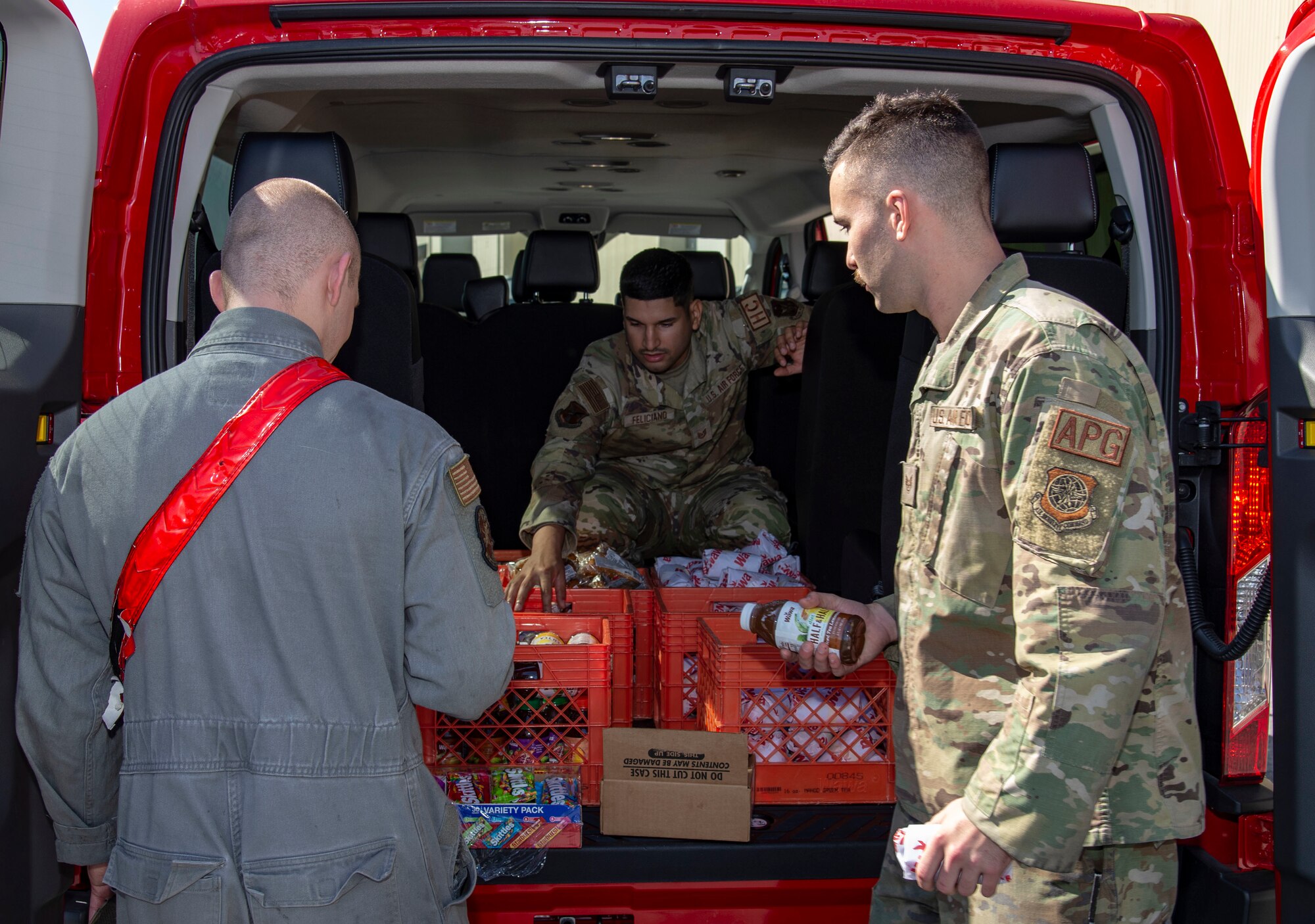 Tech. Sgt. Eric Feliciano, center, 512th Airlift Wing religious affairs airman, offers drinks, sandwiches and snacks to aircraft maintainers during a Friends on the Flight Line visit at Dover Air Force Base, Delaware, Oct. 11, 2022. The Holy Roller van made numerous stops on the flight line and at the 436th Maintenance Squadron Isochronal Dock offering items provided by the United Service Organizations. (U.S. Air Force photo by Roland Balik)