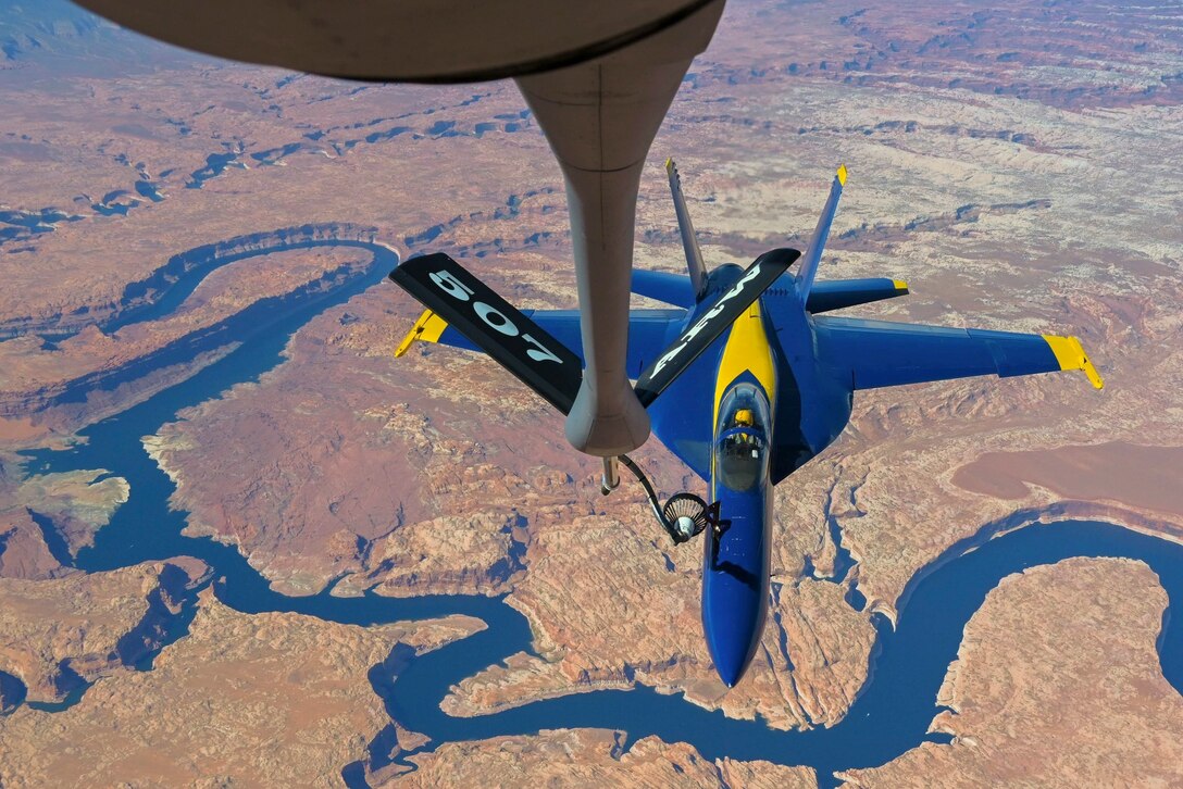 An aircraft receives fuel from another aircraft while flying over a body of water.