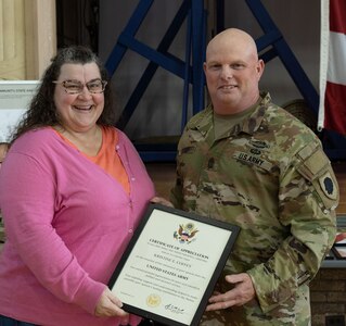Sgt. Maj. Jason S. Coffey, of Galion, Ohio, chief operations noncommissioned officer, 244th Digital Liaison Detachment, based in Chicago, presents a certificate of appreciation to his wife, Kristine, during a retirement ceremony Oct. 15 at the Northwest Armory in Chicago.