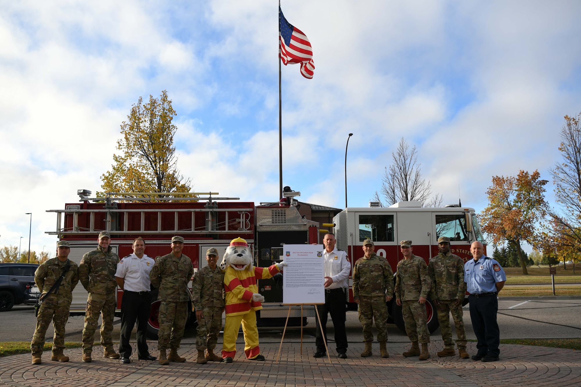 Sparky the Fire Dog, members of the 319th Civil Engineer Squadron fire department and 319th Reconnaissance Wing leadership pose for a photo with the signed 2022 National Fire Prevention Week proclamation Oct. 6, 2022, at Grand Forks Air Force Base, North Dakota. The 319th CES Fire Department supports the NFPW campaign annually in order to educate base residents and community members on fire-related emergencies. (U.S. Air Force Photo by Senior Airman Ashley Richards)
