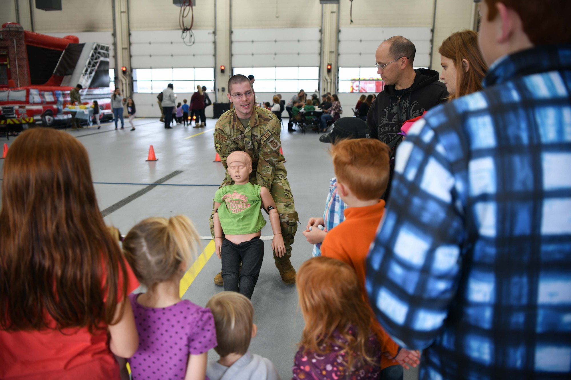 Airman Joshua Nicholson, 319th Civil Engineer Squadron firefighter demonstrates how to drag a person during the junior fire fighter challenge, Oct. 15, 2022, at Grand Forks Air Force Base, North Dakota. The 2022 Fire Prevention Week’s campaign was, “Fire won’t wait. Plan your escape.” Members of the fire department worked to educate the community about simple but important actions they can take to keep themselves and those around them safe from home fires. (U.S. Air Force Photo by Senior Airman Ashley Richards)