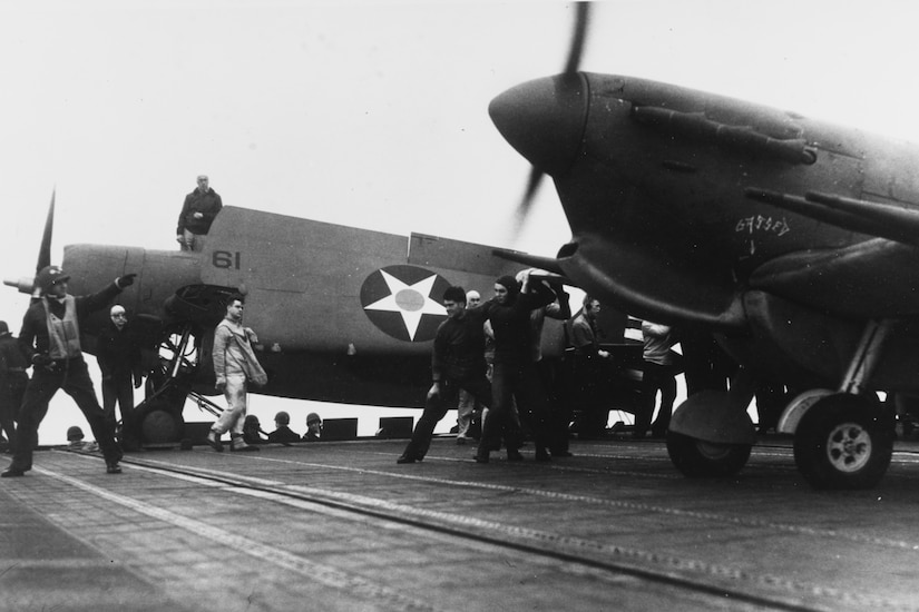 Men wave toward an airplane with propellers moving.