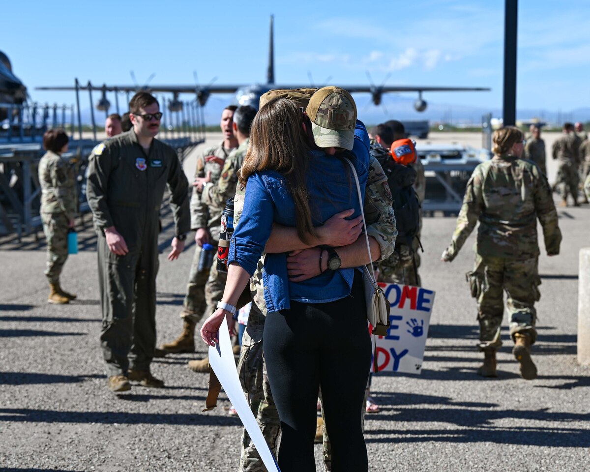 A photo of a man in uniform hugging his partner.