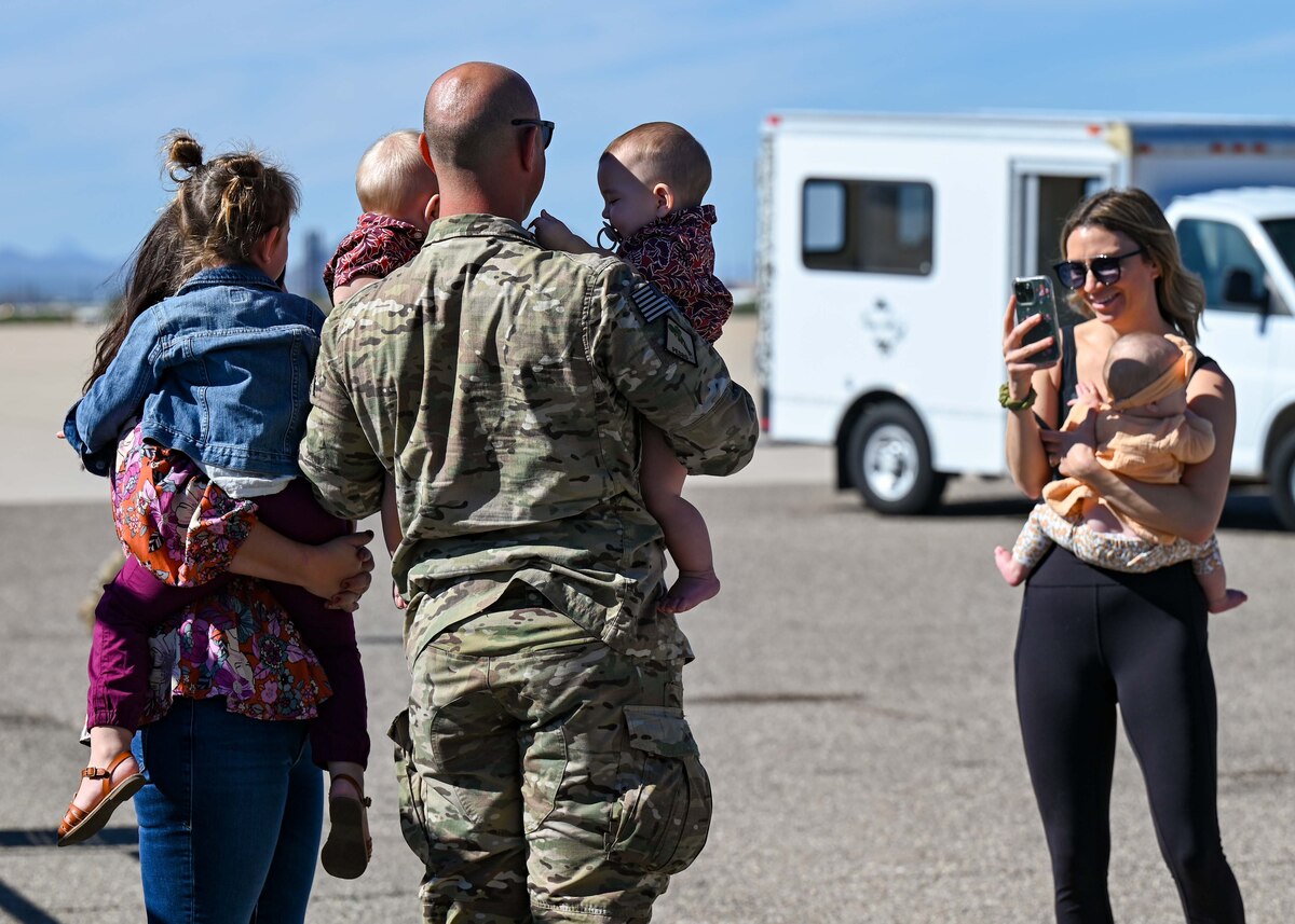 A photo of a husband, wife and their three kids posing for a photo.