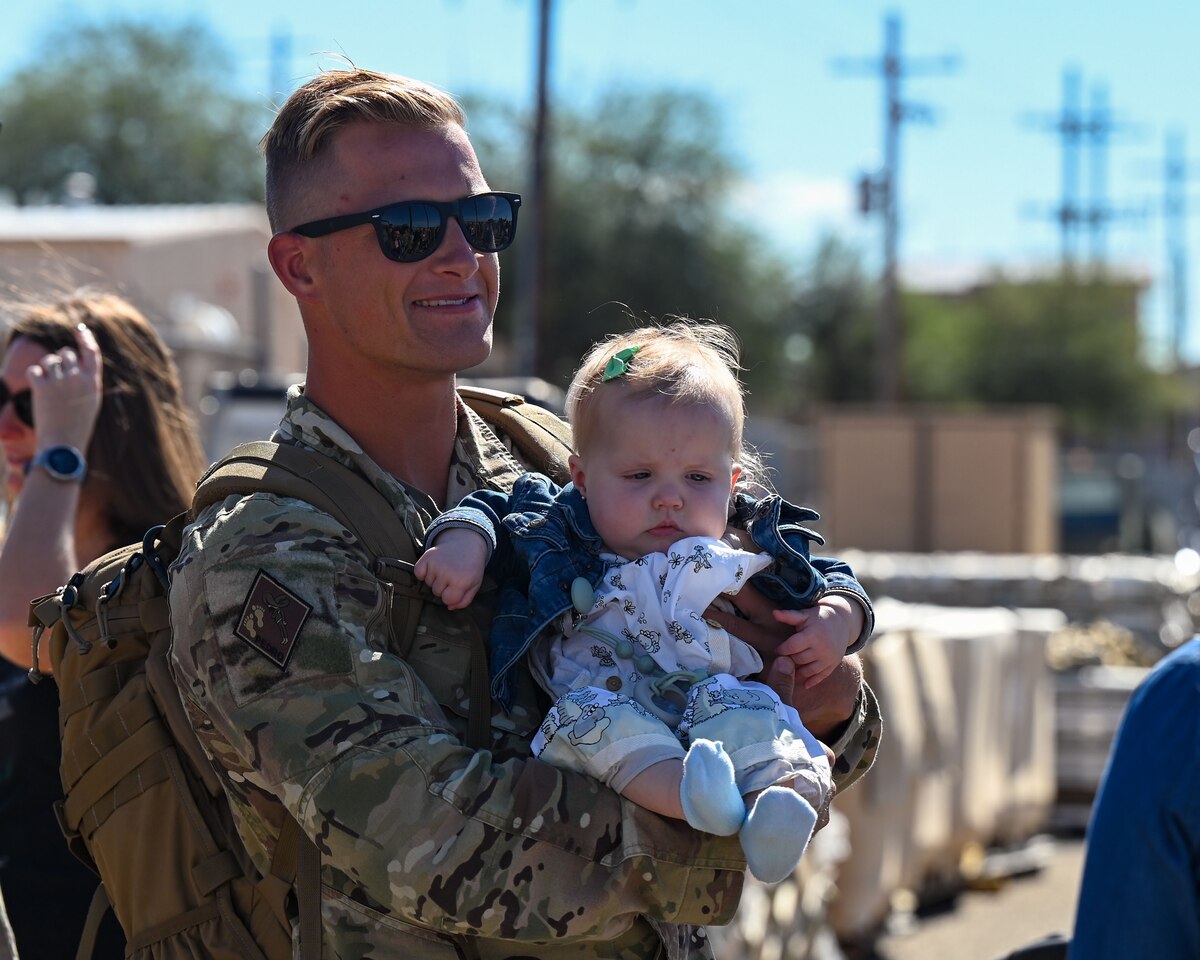 A photo of a man in uniform holding his young child.