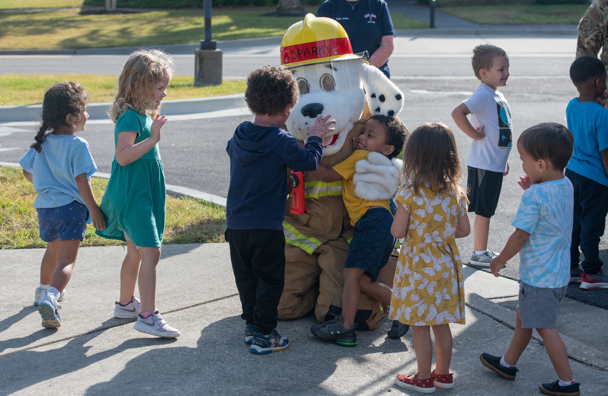 A child from the Child Development Center receives a hug from Sparky the fire dog, the official mascot of the National Fire Protection Association during the Fire Prevention Week tour at the CDC on Keesler Air Force Base, Mississippi, Oct. 13, 2022. Throughout the week the Keesler Fire Department conducted random fire drills, toured various facilities with Sparky the fire dog, passed out fire safety information and fire hats for children. (U.S. Air Force Photo by Andre' Askew)