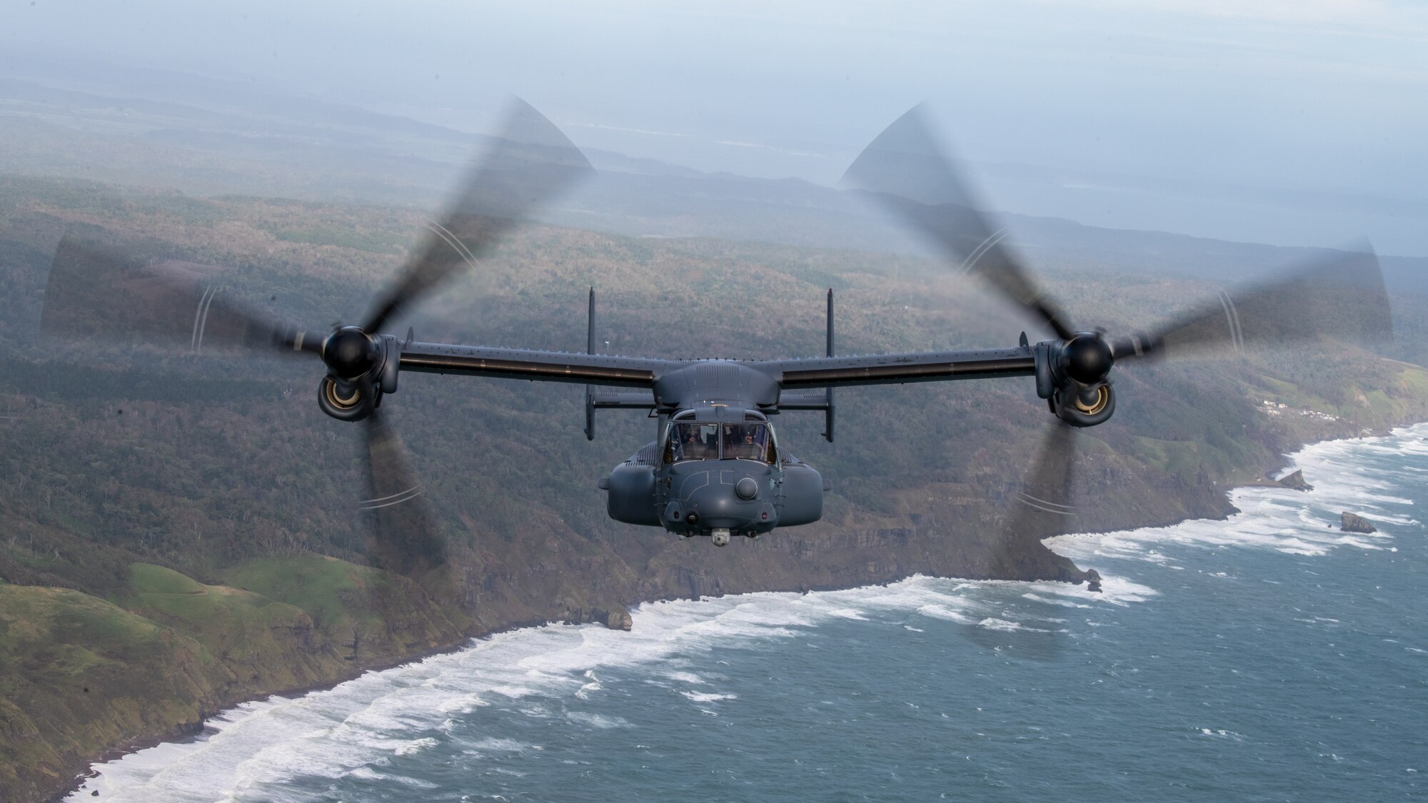 A CV-22 Osprey flies over a beach